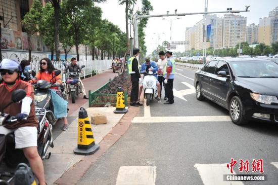 8月3日,一辆行走在机动车道的电动车被拦下。从8月1日起,昆明市交警支队开始设点推行整治非机动车违法新模式,违法驾驶员需在街边设置的警示教育点观看警示片、抄写相关交通安全法律法规,并接受《非机动车违法驾驶人安全教育测试》。<a target='_blank' href='U020191008612987506758.com/'>中新社</a>记者 刘冉阳 摄